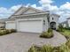 Charming single-Gathering home featuring a two-car garage, a brick driveway, and lush landscaping, presenting a welcoming curb appeal at 18002 Franklin Park Ct, Venice, FL 34293