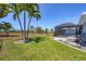 Expansive backyard featuring lush green grass and tropical palm trees surrounding a screened in pool and patio at 194 Sportsman Rd, Rotonda West, FL 33947