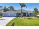 Inviting front exterior showcasing a lush lawn, palm trees, and a two-car garage at 194 Sportsman Rd, Rotonda West, FL 33947