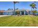 Beautiful blue home features a lush lawn, palm trees, and a two-car garage at 194 Sportsman Rd, Rotonda West, FL 33947