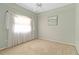 Bright bedroom features neutral carpet, ceiling fan, a window dressed with elegant sheer curtains, and a beach themed art piece at 201 Bayside Ct, Nokomis, FL 34275