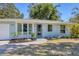 The front exterior of the home boasts stone mulch, healthy plants, and a brick walkway to the front door at 203 Palm Ave, Nokomis, FL 34275