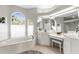 Elegant bathroom featuring garden tub, vanity area with great mirrors, and arch windows providing natural light at 2187 Calusa Lakes Blvd, Nokomis, FL 34275