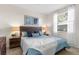 Bright bedroom featuring a window, blue bedding, and two rustic wood nightstands with lamps at 2187 Calusa Lakes Blvd, Nokomis, FL 34275