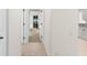 Hallway featuring tile and carpet flooring, leading to the front door with kitchen on the right at 2187 Calusa Lakes Blvd, Nokomis, FL 34275