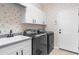 Functional laundry room with modern washer, dryer, sink, and plenty of cabinet storage at 2187 Calusa Lakes Blvd, Nokomis, FL 34275