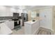 Charming kitchen featuring stainless steel appliances, white cabinetry, mosaic backsplash, and a quartz countertop island at 230 Santa Maria St # 333, Venice, FL 34285