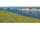 Wide shot of the canal, green lawn, and neighborhood homes under a bright blue sky at 233 Rotonda Cir, Rotonda West, FL 33947