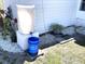 Efficient rainwater collection system with a large white tank for sustainable gardening practices at 235 Trailorama Dr, North Port, FL 34287