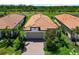 Aerial view of the home with its beautiful terracotta roof, well-manicured landscaping, and a paver driveway at 24153 Spartina Dr, Venice, FL 34293