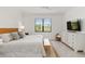 Comfortable bedroom with a queen-size bed, white dresser, and a charming woven chair at 24153 Spartina Dr, Venice, FL 34293