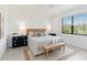 Bright bedroom with a queen-size bed, wooden bench, and view to a green outdoor space at 24153 Spartina Dr, Venice, FL 34293
