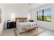 Bright bedroom with a queen-size bed, wooden bench, and view to a green outdoor space at 24153 Spartina Dr, Venice, FL 34293