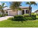 Charming home with a well-manicured lawn, paver driveway, and lush landscaping at 24153 Spartina Dr, Venice, FL 34293