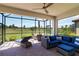 Screened-in patio with wicker furniture, ceiling fan, and a view of the lush backyard at 24153 Spartina Dr, Venice, FL 34293