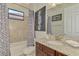 Well-lit bathroom with granite countertop vanity, tiled shower/tub, and decorative window at 24193 Gallberry Dr, Venice, FL 34293