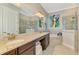Bright bathroom featuring double sinks, granite countertops, a soaking tub, and a glass-enclosed shower at 24193 Gallberry Dr, Venice, FL 34293