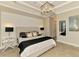 Well-lit primary bedroom with a decorative accent wall, stylish bedside tables, and a modern chandelier at 24193 Gallberry Dr, Venice, FL 34293