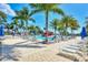 Resort-style pool area with lounge chairs, palm trees, and blue umbrellas for shade on a sunny day at 24193 Gallberry Dr, Venice, FL 34293