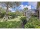 Landscaped backyard showcasing mature trees, lush shrubbery, and a screened-in patio, creating a private and serene outdoor space at 2542 Cortenova Ct, Venice, FL 34292