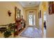 Bright foyer with decorative rug, mirror, console table, and view of the decorative front door at 2542 Cortenova Ct, Venice, FL 34292
