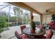 Screened lanai with a round table and chairs, offering outdoor living and view of lush landscaping at 2542 Cortenova Ct, Venice, FL 34292