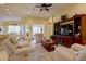 Comfortable living room with a large entertainment center, ceiling fan, and open to the dining area at 2542 Cortenova Ct, Venice, FL 34292