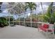 Screened-in patio with white bench, outdoor rug, and views of lush landscaping, offering a relaxing outdoor space at 2542 Cortenova Ct, Venice, FL 34292
