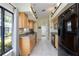 Long kitchen boasts natural wood cabinets, black appliances, and a garden window at 269 Southampton Dr # 303, Venice, FL 34293