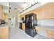 Bright kitchen with black appliances, ample wood cabinetry, and tile flooring at 269 Southampton Dr # 303, Venice, FL 34293