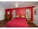 Spacious bedroom featuring wood floors, a ceiling fan, and a vibrant red accent wall at 271 Manor Rd, Venice, FL 34293