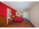 Relaxing bedroom featuring wood floors, a ceiling fan, and a vibrant red accent wall at 271 Manor Rd, Venice, FL 34293