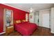Cozy bedroom featuring wood floors, a ceiling fan, and a vibrant red accent wall at 271 Manor Rd, Venice, FL 34293
