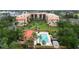 Aerial view showcasing a complex with a pool, tennis courts, landscaping, and parking at 3006 Caring Way # 304, Port Charlotte, FL 33952
