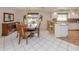 Bright dining area featuring a wooden dining table and chairs, with breakfast bar into kitchen and decorative window at 3167 Night Heron Ln, Venice, FL 34293