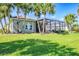 Inviting backyard with manicured lawn, palm trees, and a screened lanai, ideal for outdoor living at 3337 Pine Shadow Cir, North Port, FL 34287