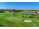 Aerial view of an expansive green golf course with sand traps and a serene lake, a golfer's paradise at 3337 Pine Shadow Cir, North Port, FL 34287