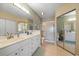 Modern bathroom with double sinks, tiled floors, and a glass-enclosed shower at 414 Laurel Lake Dr # 203, Venice, FL 34292