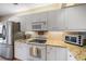 Well-lit kitchen with stainless steel refrigerator, white cabinetry, granite countertops and modern appliances at 414 Laurel Lake Dr # 203, Venice, FL 34292