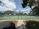 Gated entry to community tennis courts with a view of the net and seating at 414 Laurel Lake Dr # 203, Venice, FL 34292