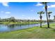 Scenic water view of condo complex overlooking lake with lillypads and lush greenery and palm trees at 414 Laurel Lake Dr # 203, Venice, FL 34292