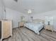 Bright bedroom featuring gray wood floors, wicker furniture, ceiling fan, and windows with natural light at 425 Pirates Pt, North Port, FL 34287