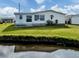 Well-maintained home with lush green lawn and easy access to a tranquil pond, perfect for relaxation at 425 Pirates Pt, North Port, FL 34287