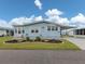 Charming home featuring light blue siding, a well-manicured lawn, and a decorative garden at 443 Landsedge Dr, North Port, FL 34287