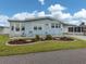 A cozy residence featuring light blue siding, a lush green lawn, and meticulous landscaping at 443 Landsedge Dr, North Port, FL 34287