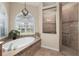 Elegant bathroom with a soaking tub, walk-in shower, and a large window with plantation shutters at 4641 Gaeta Dr, Venice, FL 34293