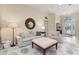 Bright living room featuring neutral furniture, a large round mirror, and a view into the entryway, enhancing the cozy feel at 4641 Gaeta Dr, Venice, FL 34293