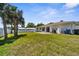 Lush backyard featuring a wide expanse of grass, palm trees, and the exterior of the house at 511 Porpoise Rd, Venice, FL 34293