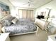 Bright bedroom features a ceiling fan, bed with decorative pillows and a white dresser with a mirror at 537 Amberjack Dr, North Port, FL 34287