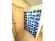 Shower stall with a patterned blue shower curtain and an access door with hooks for hanging towels at 537 Amberjack Dr, North Port, FL 34287